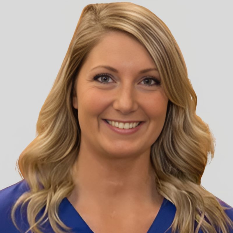 Dr. Paige Parker-Lewis, audiologist, smiling in royal blue scrubs